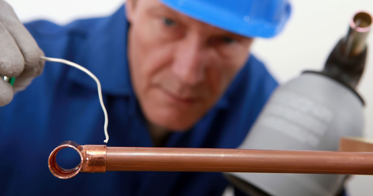 man soldering a copper pipe