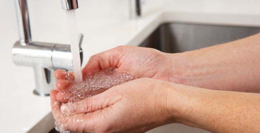 person filling hands with water under kitchen faucet