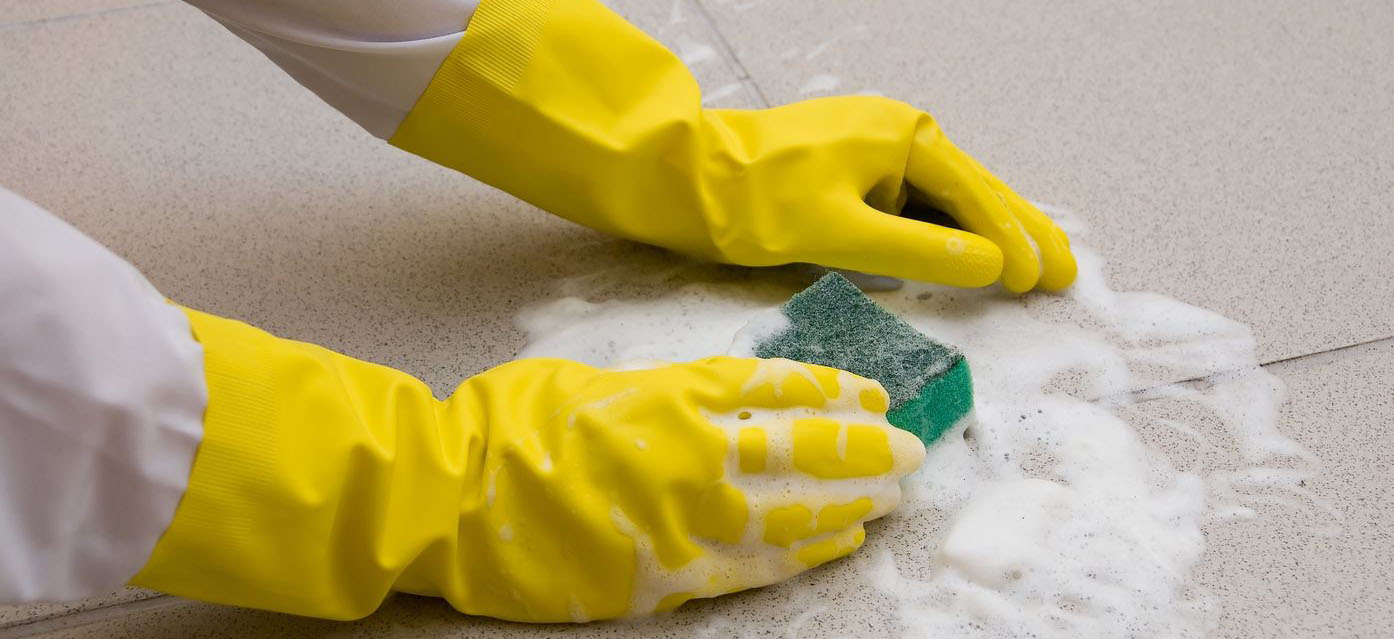 person with dish washing gloves cleaning bathroom floor